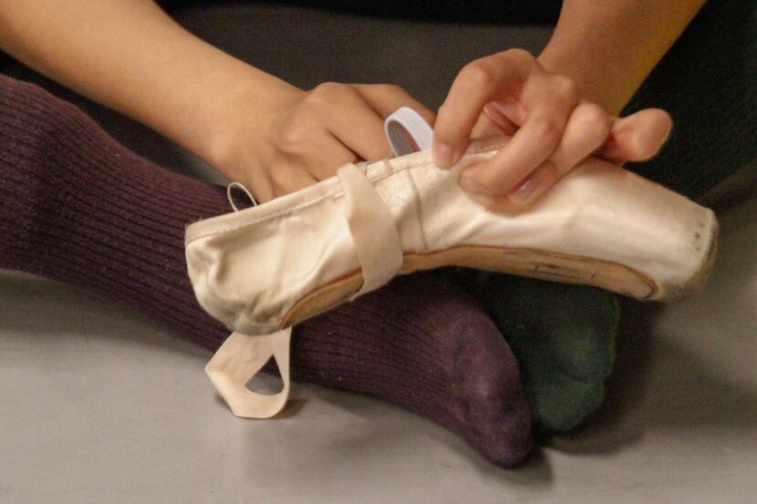 Wang Yuanyuan, artistic director of Beijing Dance Theater, repairs a pointe shoe being used...