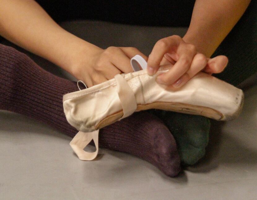 Wang Yuanyuan, artistic director of Beijing Dance Theater, repairs a pointe shoe being used...