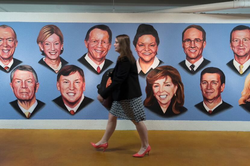 A passerby walks past a mural featuring the justices of the Fifth Court of Appeals after the...
