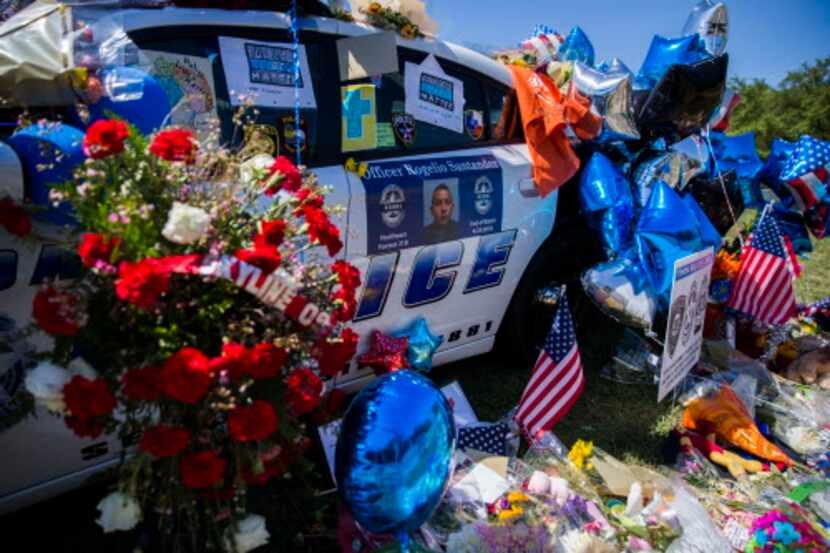 Un patrullero de la policía de Dallas en Northwest Highway está repleto de flores en...