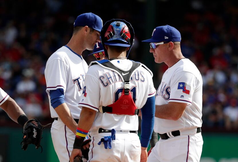 Cole Hamels (izq.) habla con el mánager de los Rangers, Jeff Banister. (AP Photo/Tony...