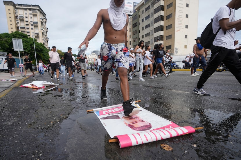 A protester steps on a campaign sign of President Nicolas Maduro during a march against hish...