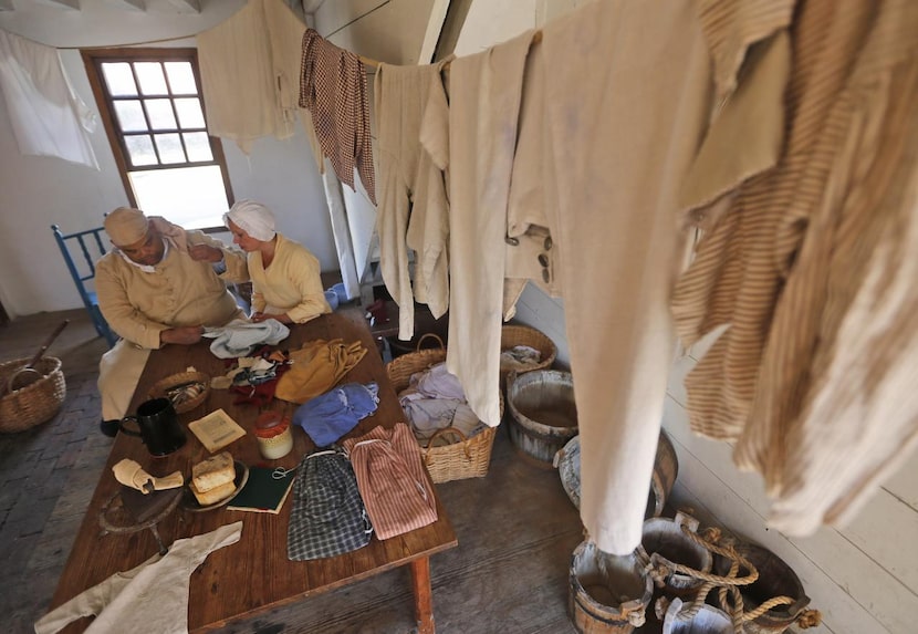 Historical  interpreter Edwin Cooke III of Williamsburg gets a sewing lesson from Lynda...