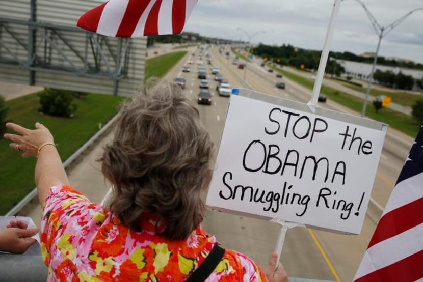 
A member of the Wylie Tea Party waves to vehicles  during a protest on July 19 for tighter...