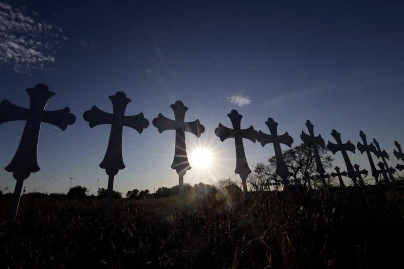 In this Nov. 6, 2017 file photo, the sun sets behind 26 crosses placed in a field before a...