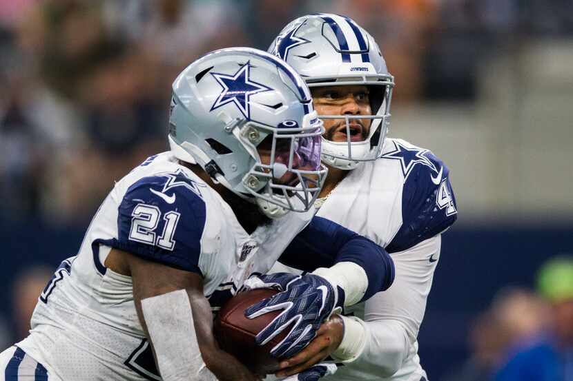Cowboys quarterback Dak Prescott (4) hands the ball off to running back Ezekiel Elliott (21)...
