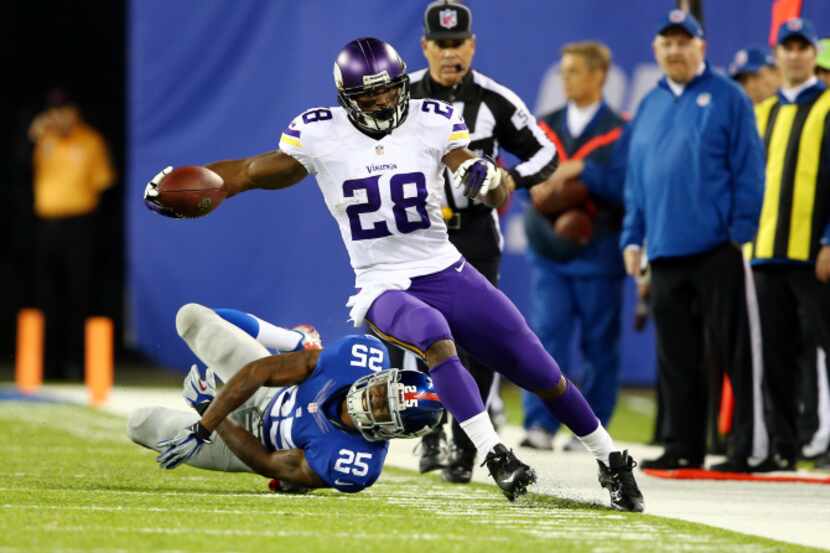 Adrian Peterson #28 of the Minnesota Vikings avoids a tackle by defensive back Will Hill #25...
