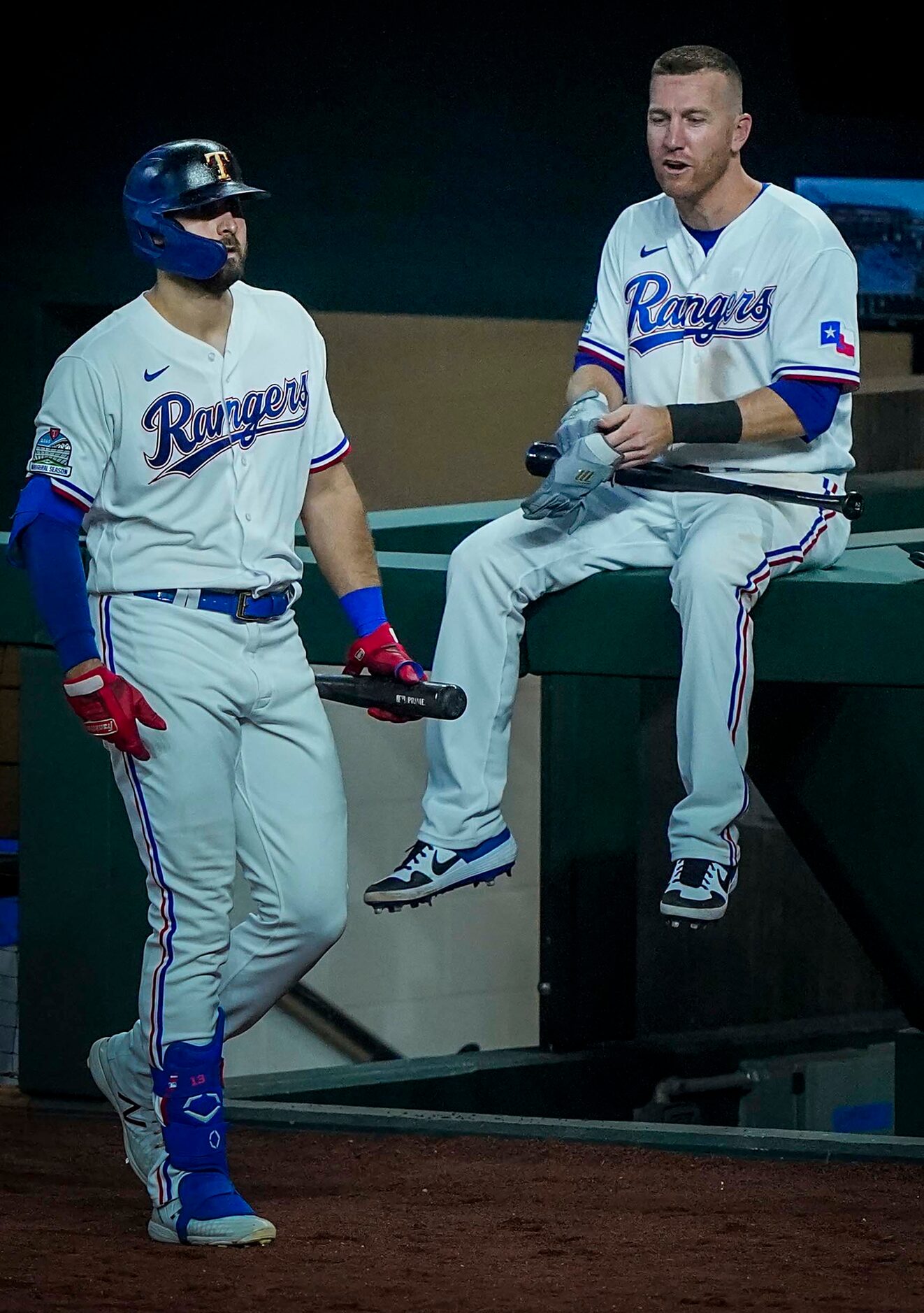 Outfielder Joey Gallo passes third baseman Todd Frazier perched atop the dugout rail as he...