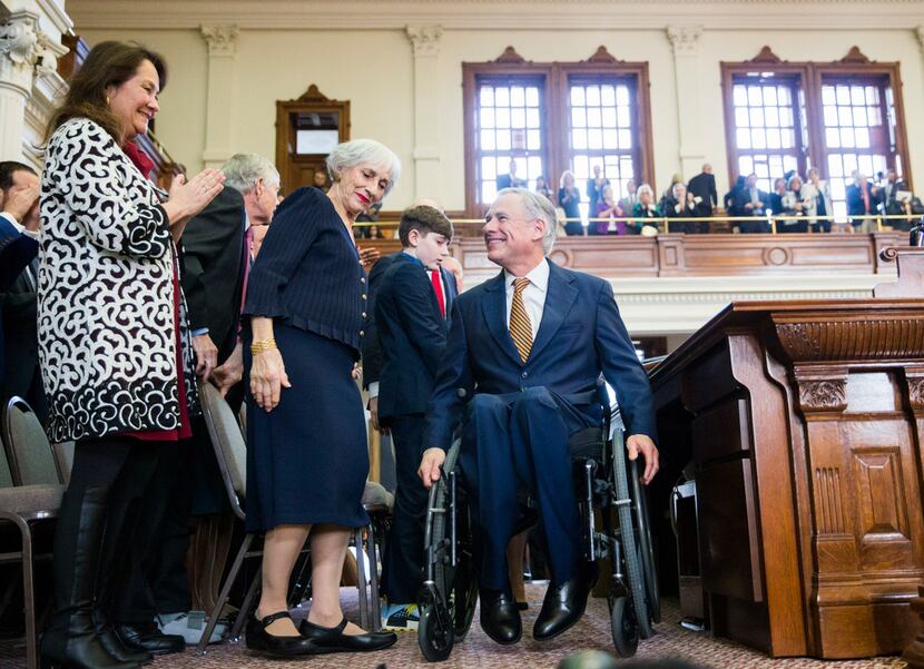 As Texas first lady Cecilia Abbott (left) looked on, Gov. Greg Abbott wheeled himself off...