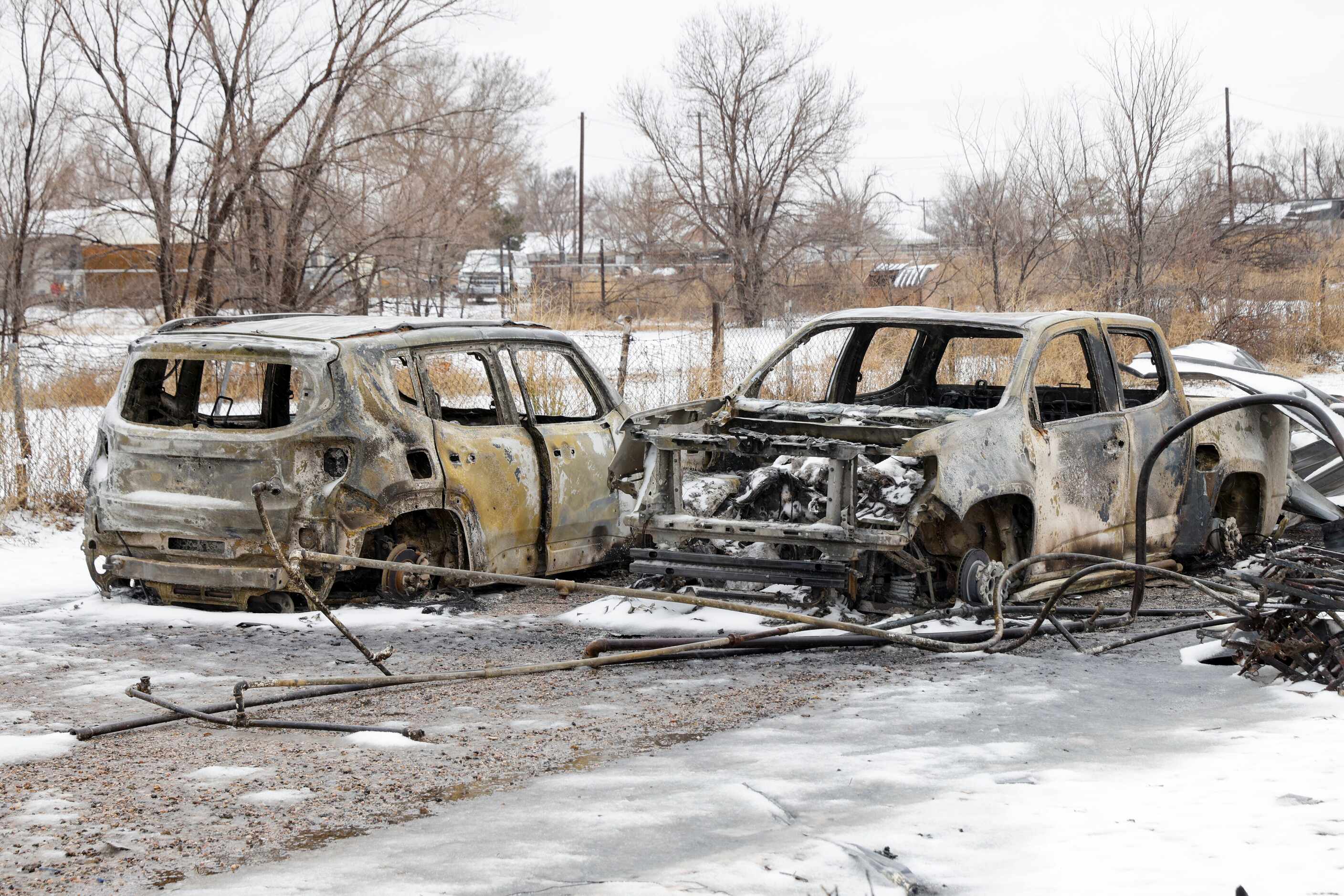 The charred remains of an SUV and pickup truck are seen after being destroyed by the...