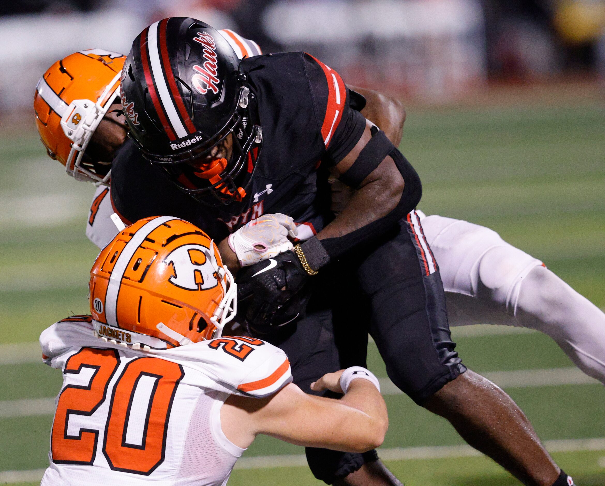 Rockwall-Heath's Malachi Tuesno(0) \is tackled by Rockwall's Cameron Marsh (4), behind, and...