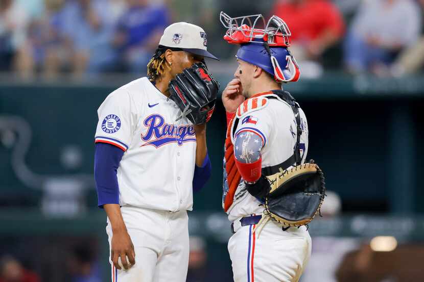 Texas Rangers relief pitcher José Ureña, left, and catcher Andrew Knizner, right, talk on...