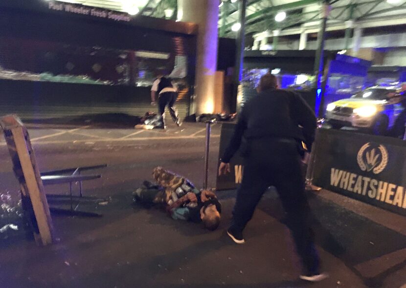 Armed police stand over what is believed to be a suspect shot at the scene of a terror...