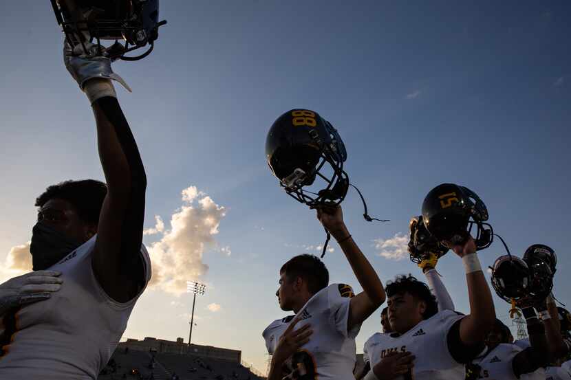 Garland High School football players put their helmets in the air during the Star-Spangled...