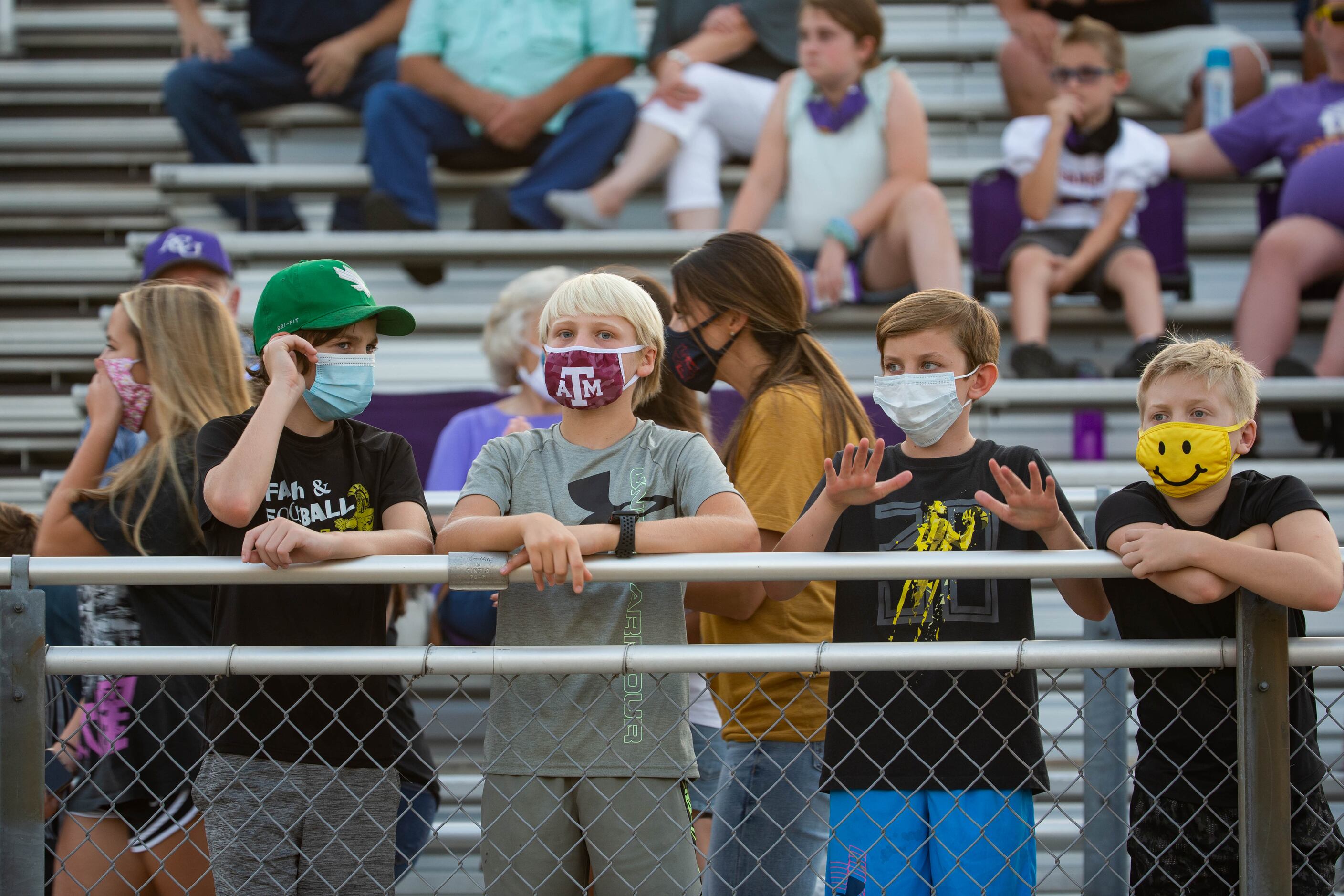 Sanger High School fans wear face masks as they wait for the start of a game against Lake...