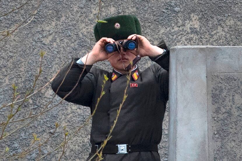 A North Korean soldier uses his binoculars to look across the Yalu river near Sinuiju,...