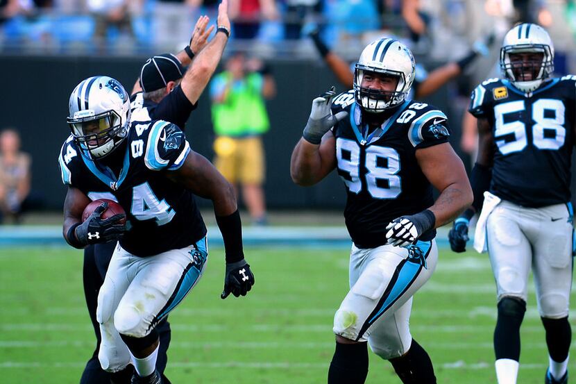 Carolina Panthers defensive end Kony Ealy, left, cradles the ball after intercepting a pass...