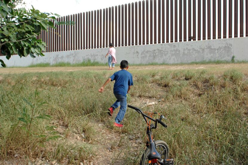 A boy runs toward a section of U.S. border fence from his backyard in the South Texas town...