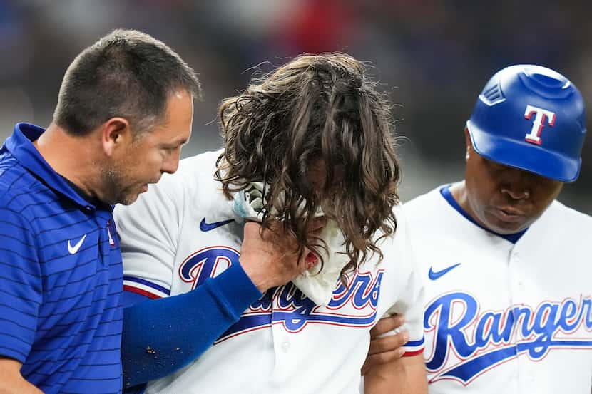 Texas Rangers outfielder Josh Smith is helped off the field after he was hit in the face...