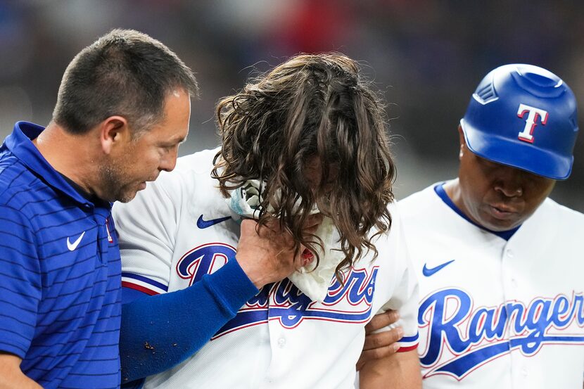 Texas Rangers outfielder Josh Smith is helped off the field after he was hit in the face...