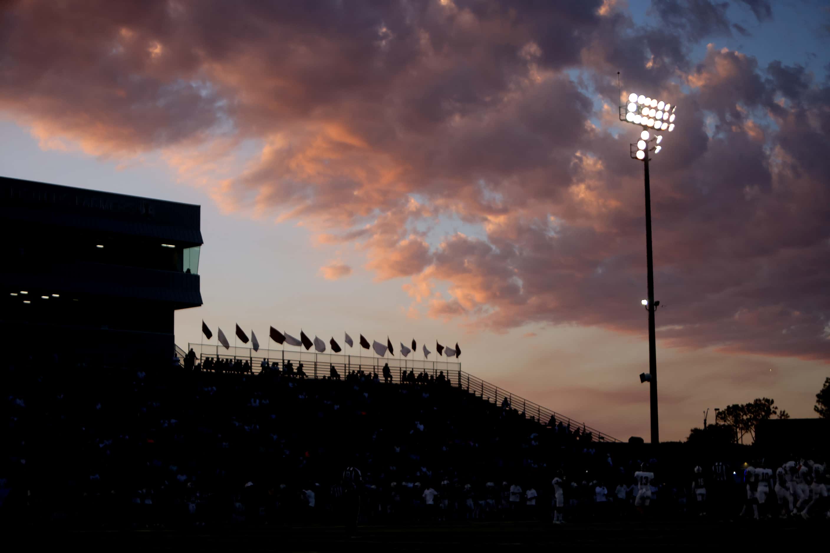 A setting sun illuminates clouds as a backdrop for a capacity crowd in attendance in the...