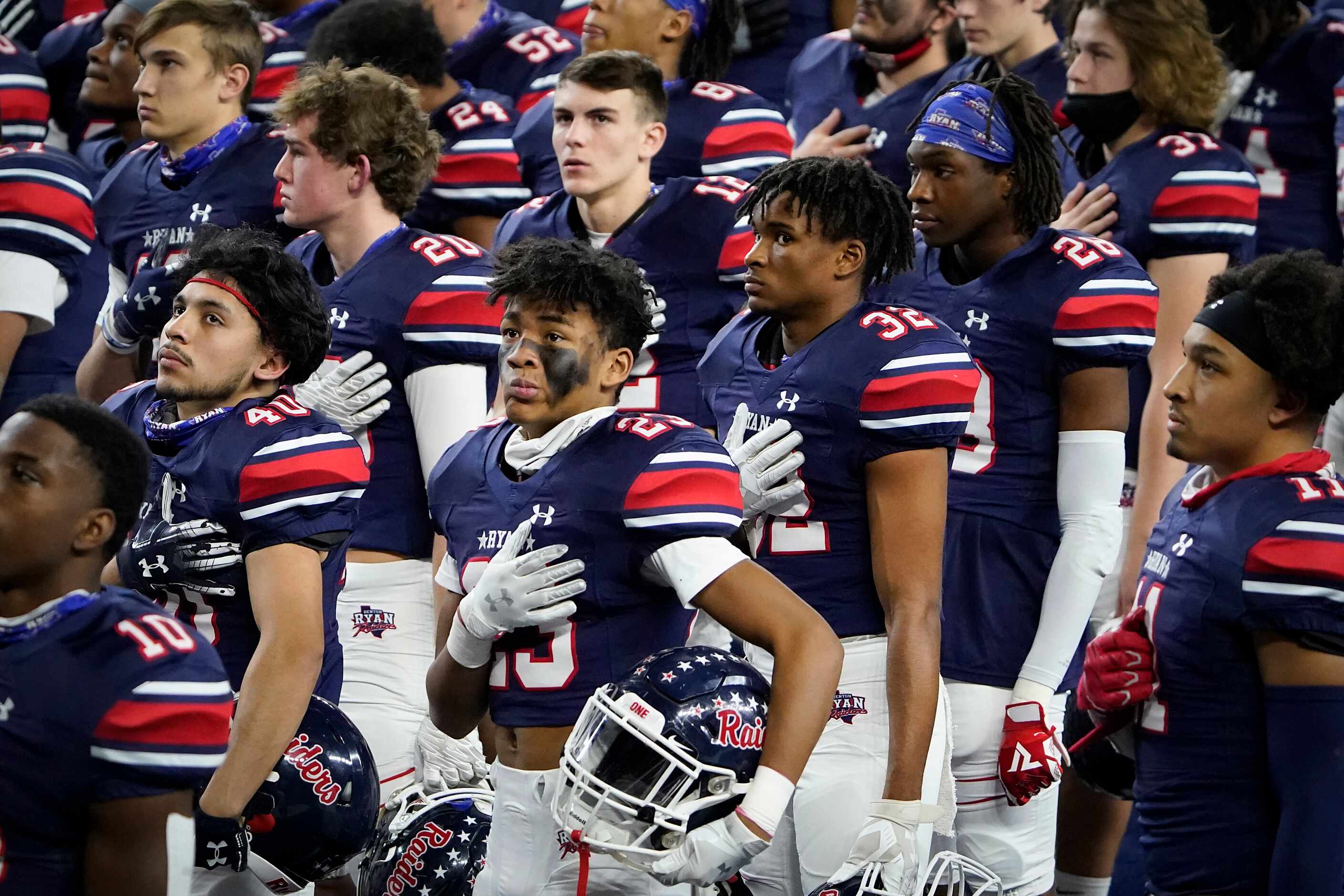 Denton Ryan players, including defensive back James Lundy (23), stand for the national...