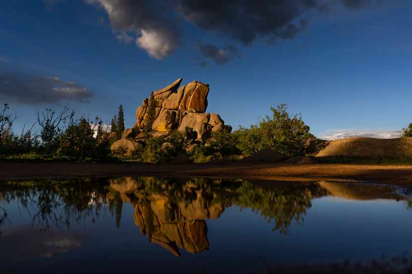 Rock formations are reflected in water after a storm near Vedauwoo Recreation Area near...