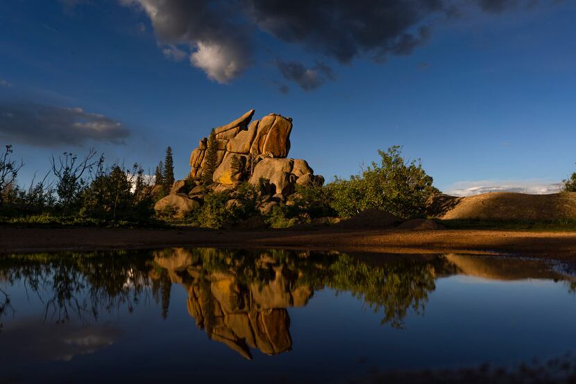 Rock formations are reflected in water after a storm near Vedauwoo Recreation Area near...