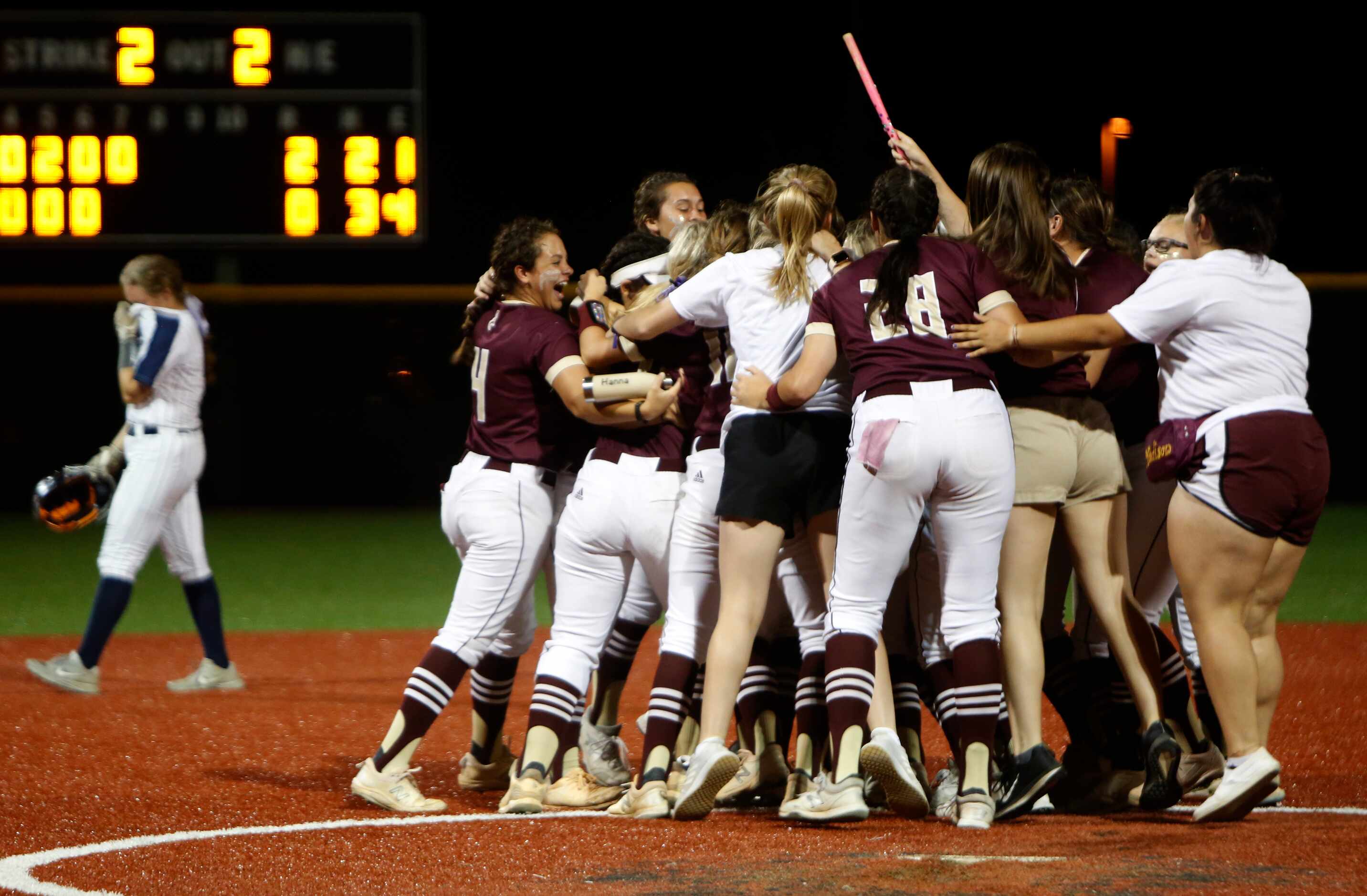 Deer Park players and fans celebrate on the field as a Flower Mound player walks back to the...