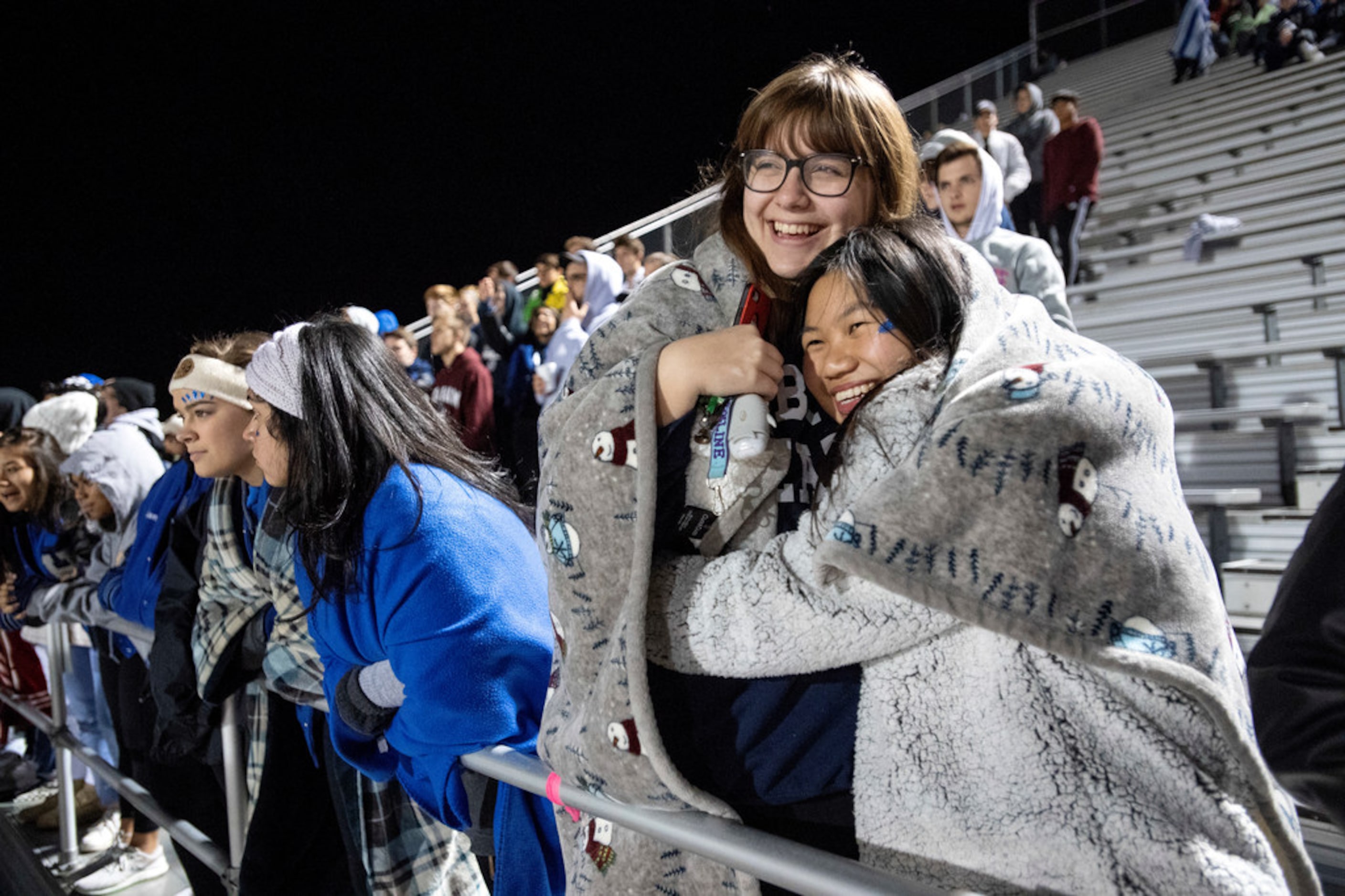 Hebron seniors Maddie Edwards, left, and Tiffany Ong huddle up for warmth before a high...