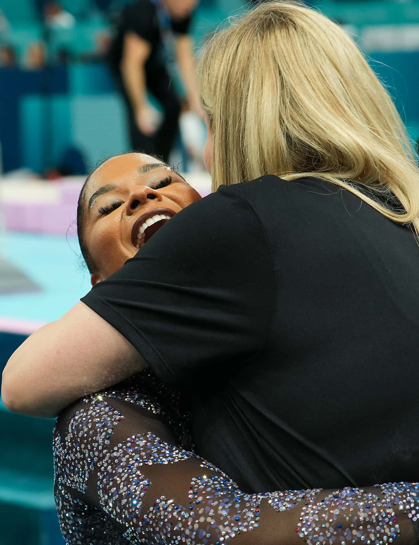 Jordan Chiles of the United States hugs coach Cecile Landi after competing on the uneven...