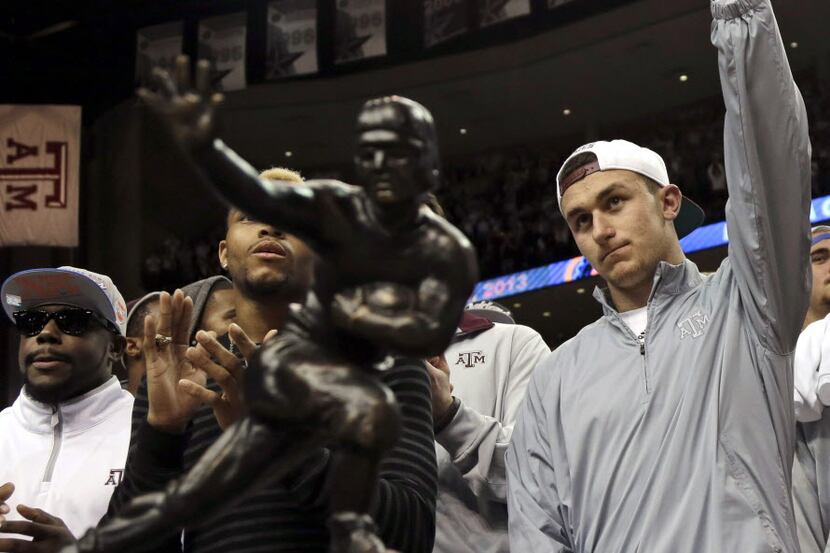 Texas A&M quarterback Johnny Manziel, right, waves to the crowd as he stands behind his...