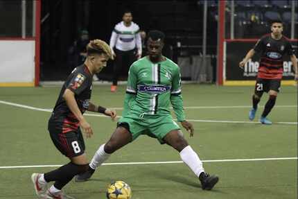 A Dallas Sidekicks player maneuvers a soccer ball on the field away from an opposing team...