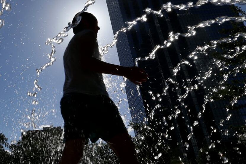 Dayana Piedra, 8, is silhouetted as she cools off at Main Street Garden Park in Dallas in...