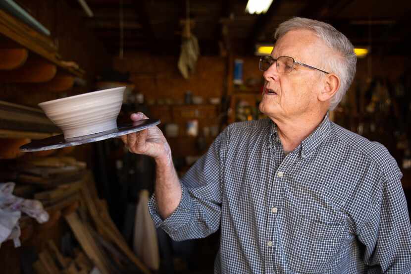 Bill Reed examines a bowl after shaping it in his garage workshop.