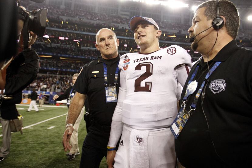 Texas A&M Aggies quarterback Johnny Manziel (2) is escorted to the trophy presentation at...