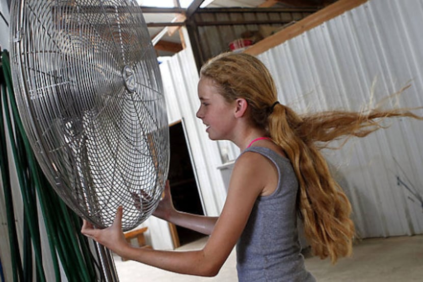 Twelve-year-old Kristen Turner of Dallas cools down in front of a fan after a short ride on...