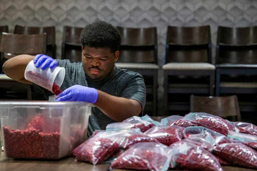 Demondric Pratt helps prepare food packets for meal kits to be distributed by Cafe Momentum...
