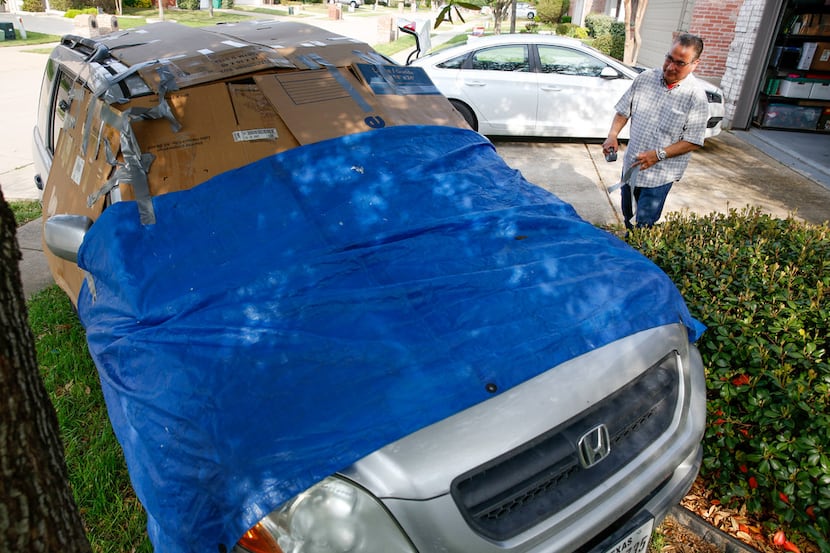 Michael Ruiz of McKinney tapes boxes and a tarp on one of his cars to protect it from hail...
