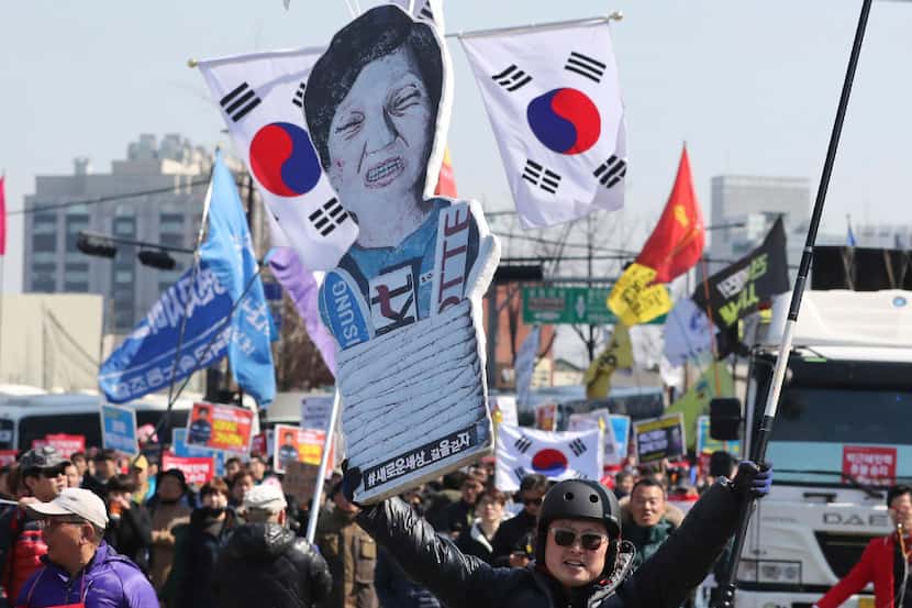 A protester carries a cutout of impeached President Park Geun-hye as they march toward the...