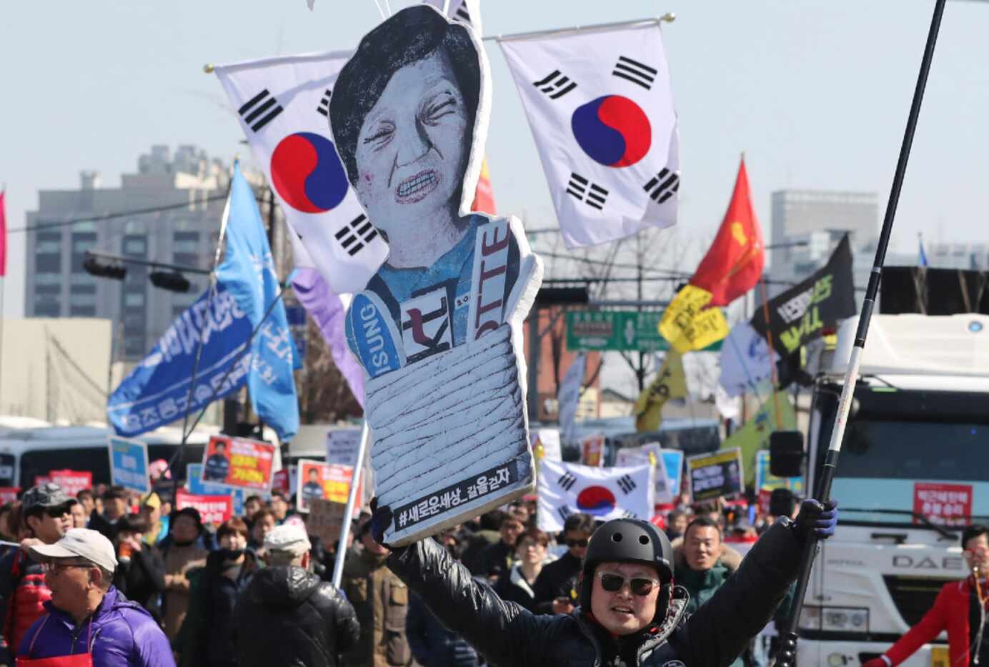 A protester carries a cutout of ousted South Korean President Park Geun-hye through the...