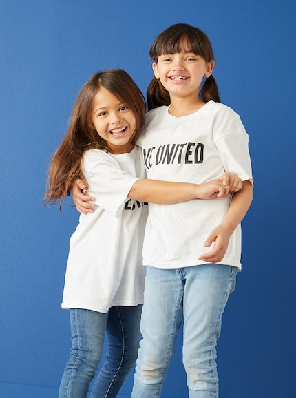 Two young girls hugging each other for a picture