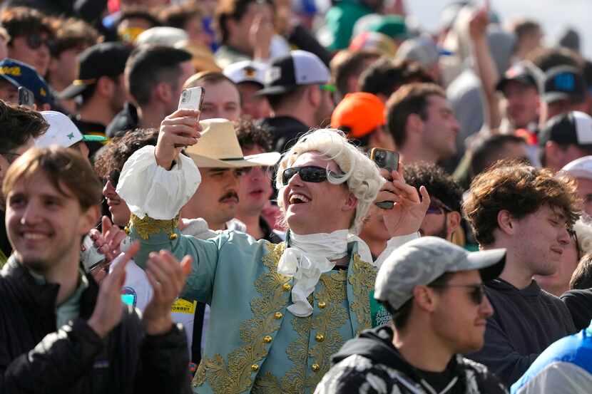 A member of the gallery at the 16th hole takes a selfie during the continuation of the...