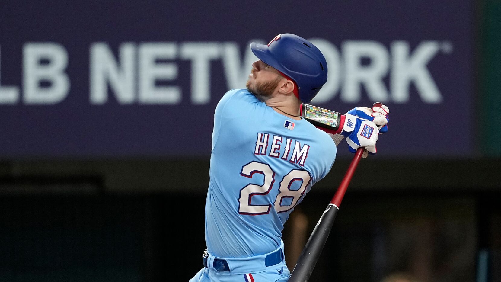 Texas Rangers' Jonah Heim follows through on a three-run home run swing in the sixth inning...