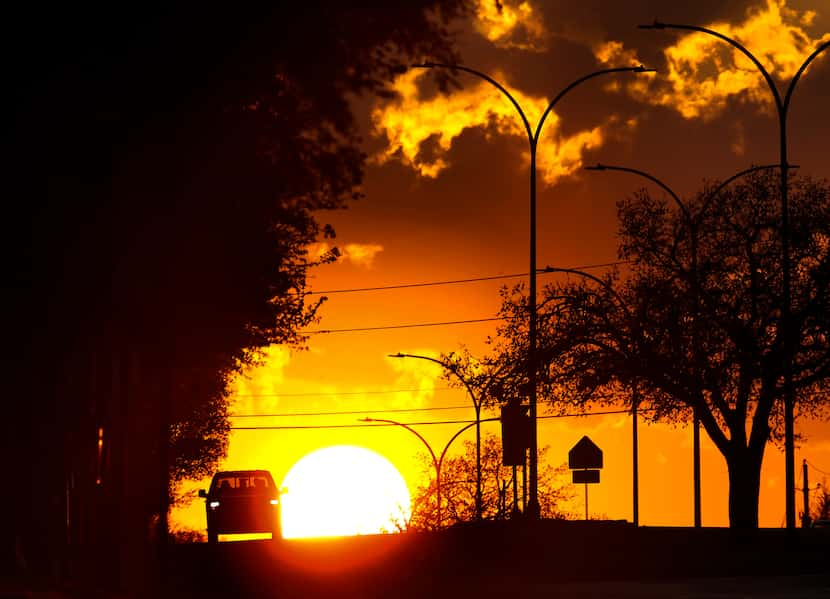 The sun appears from behind storm clouds as it sets along Lamar Blvd in North Arlington,...