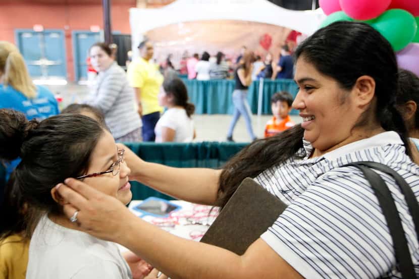 Sara Torres, 8, smiled as her mother, Lisa Angeles, tried a pair of glasses on her during...
