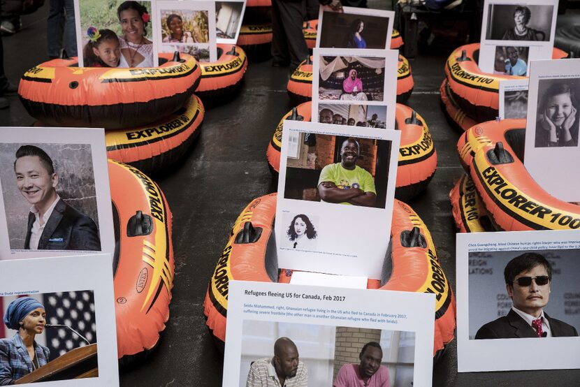 Protestors place photographs of refugees in rafts in front of the Trump Building on Wall...