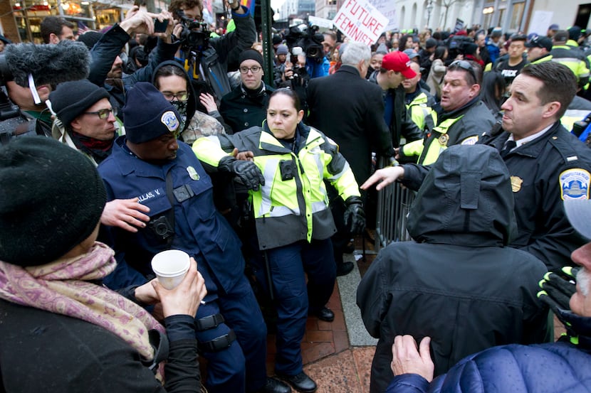 Police push back demonstrators attempting to block people entering a security checkpoint,...