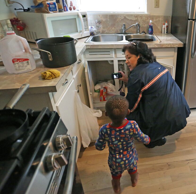 London Armstead watches as city of Dallas code inspector Diana Conde checks to see if a...