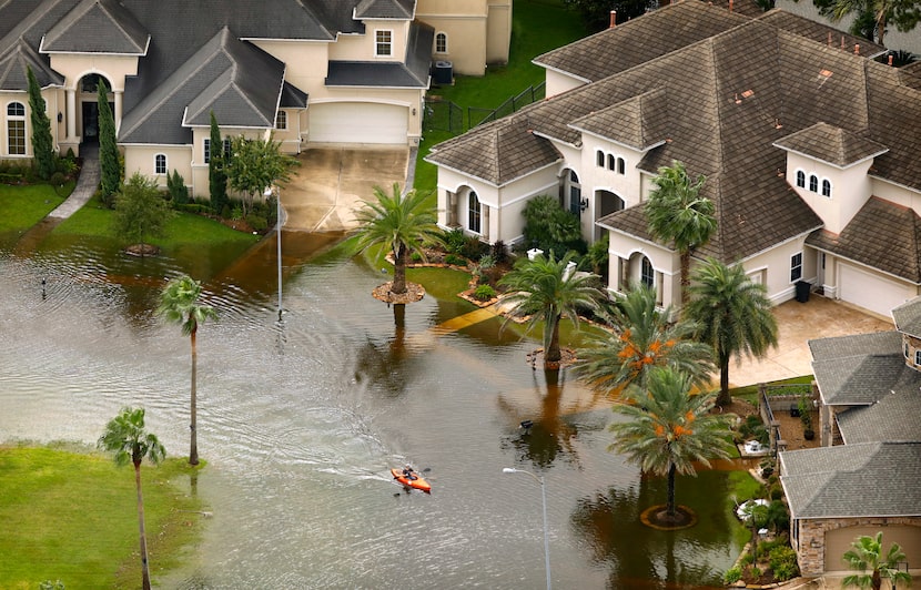 A kayaker paddles through the flooded Lakes on Eldridge neighborhood near the Addicks...